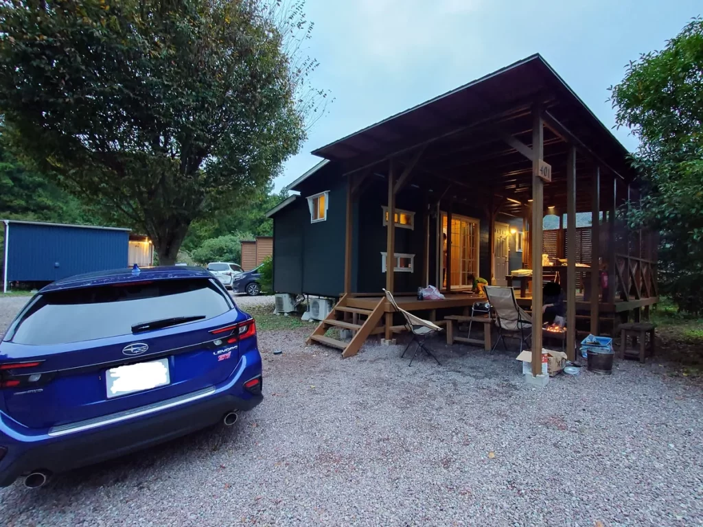 満願ビレッジオートキャンプ場のコテージと駐車場の様子